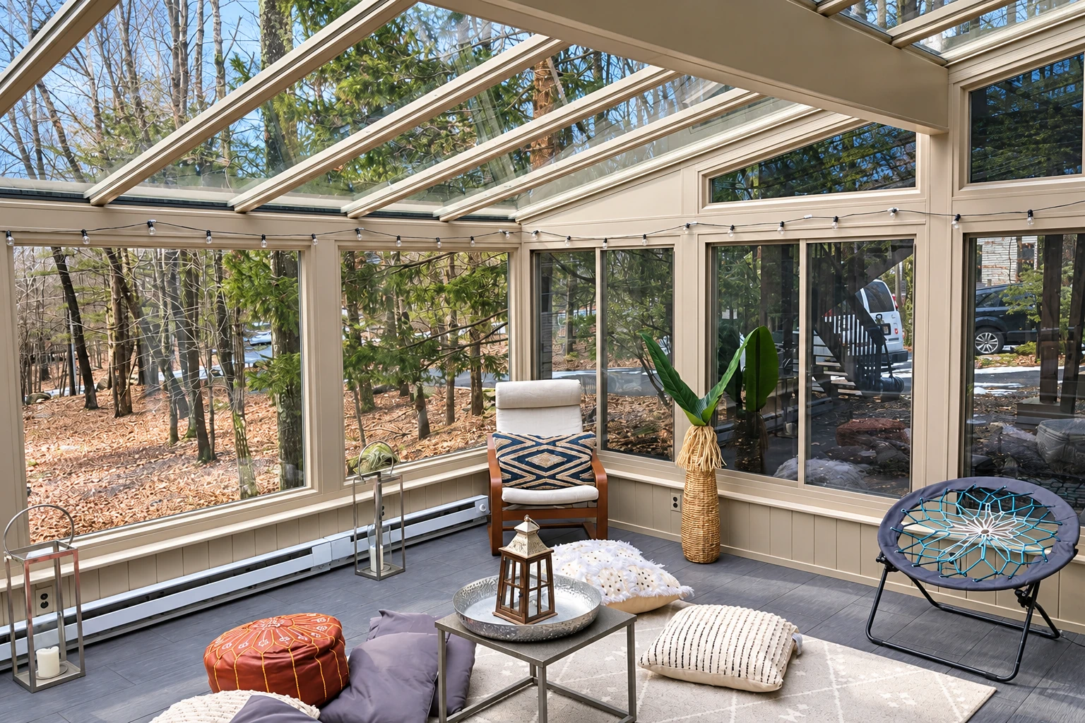 Solarium with a glass-paneled roof and walls encloses a furnished patio, with trees visible through the windows.